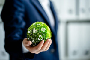 Profissional segurando esfera verde com ícones de reciclagem, indústria e CO2, representando economia circular nas empresas